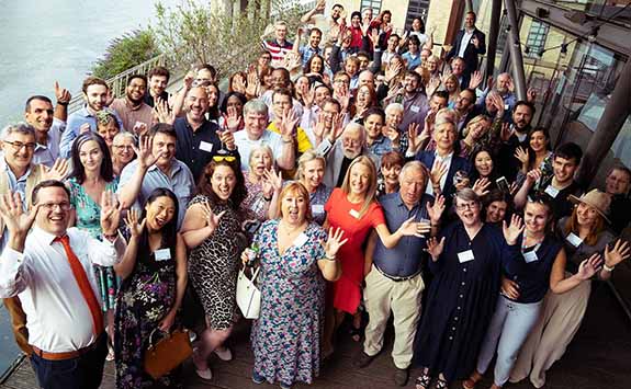 Large group of alumni smiling and waving at the camera at a alumni networking event